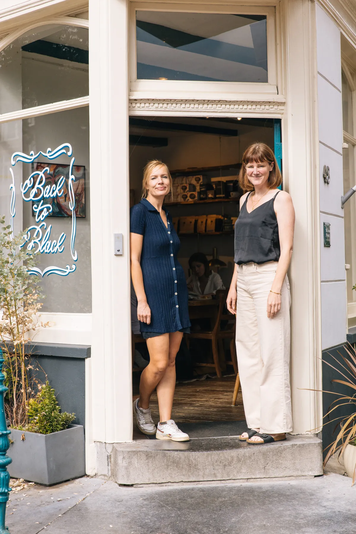Noortje and Inge, the founders of Back to Black, standing in the doorway of their first coffee bar