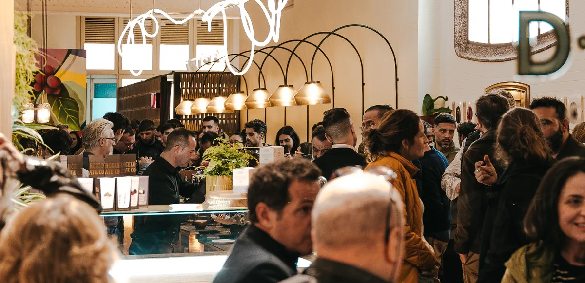 The crowded interior of D·Origen Casa Calvet, with arched windows, pendant lamps and a coffee bar