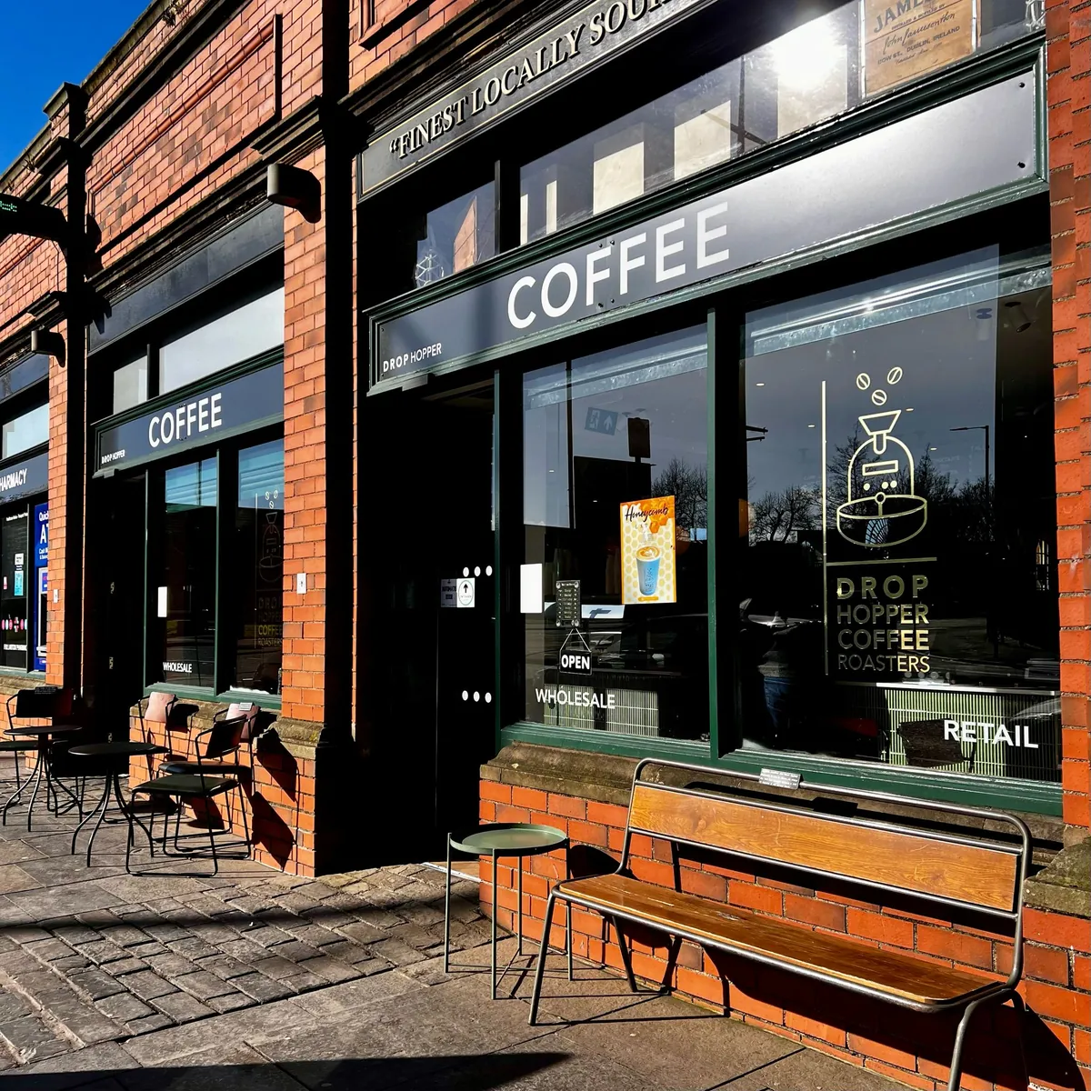 The red-brick frontage of the Drop Hopper Coffee Roasters bar and store at St George’s Market in Belfast, with a wooden bench under the window
