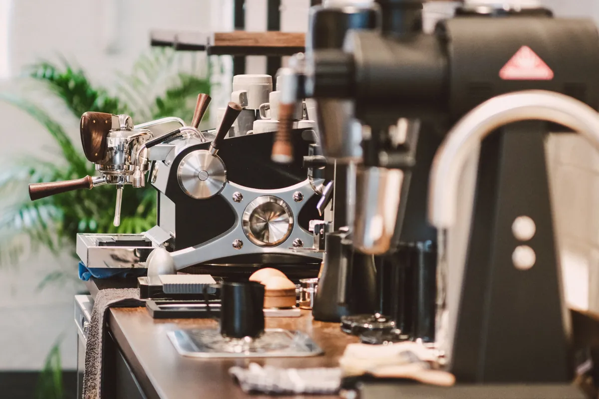 A lever espresso machine and grinders on the wooden bar at the Root & Branch roastery brew bar in Belfast