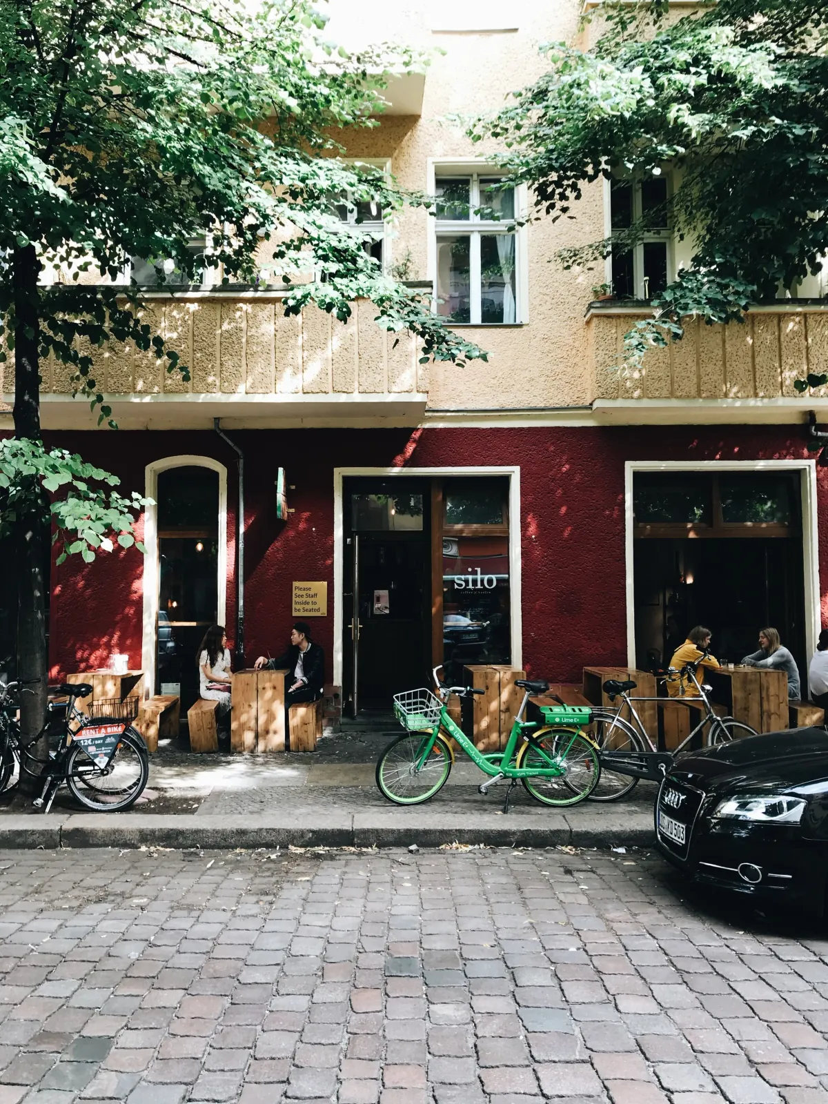 The red-fronted Silo café, with timber block seating under the trees and bicycles outside