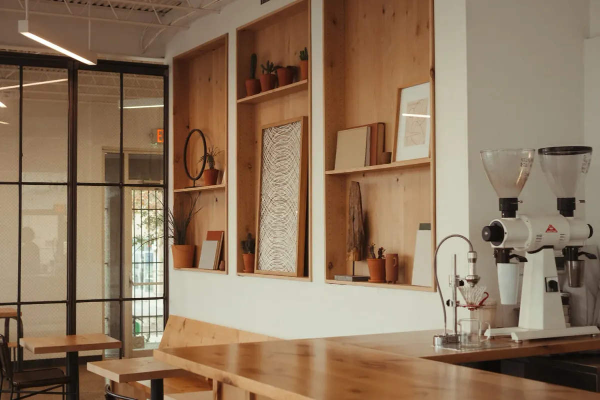 The wooden counter of a Civil Goat café, with shelves of cups, two grinders and an espresso machine beside a steel-framed glass partition