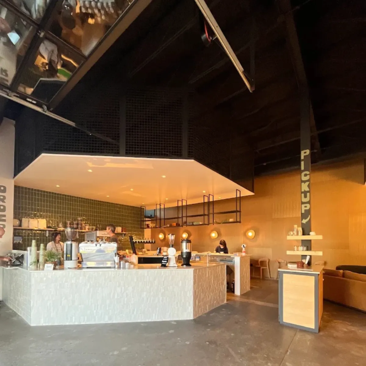 A white tiled counter with an espresso machine under a dark timber ceiling at a Civil Goat café