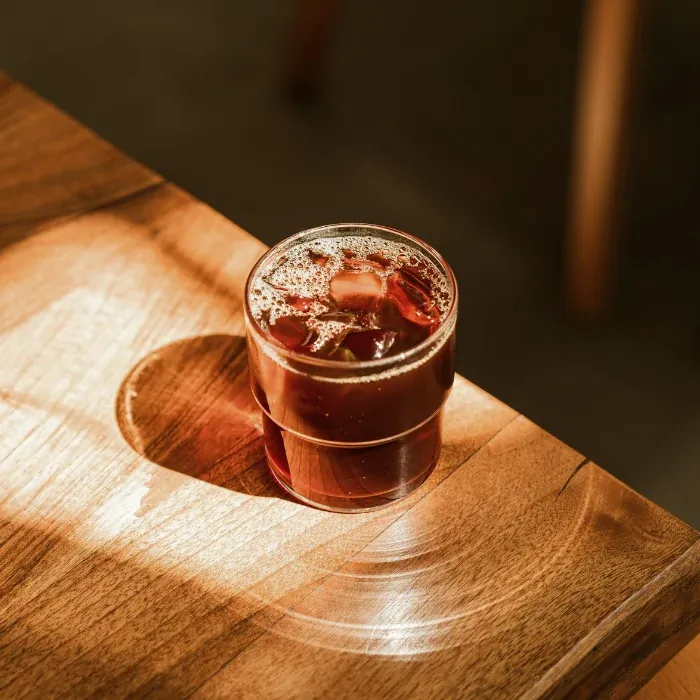 An iced coffee in a glass on a sunlit wooden table at Be Bright on Melrose