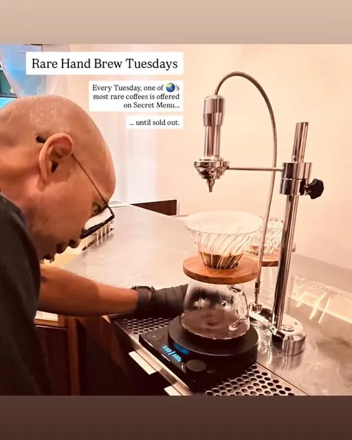 Jack leans over a pour-over stand at the Endorffeine counter, with a chrome kettle arm above a glass dripper