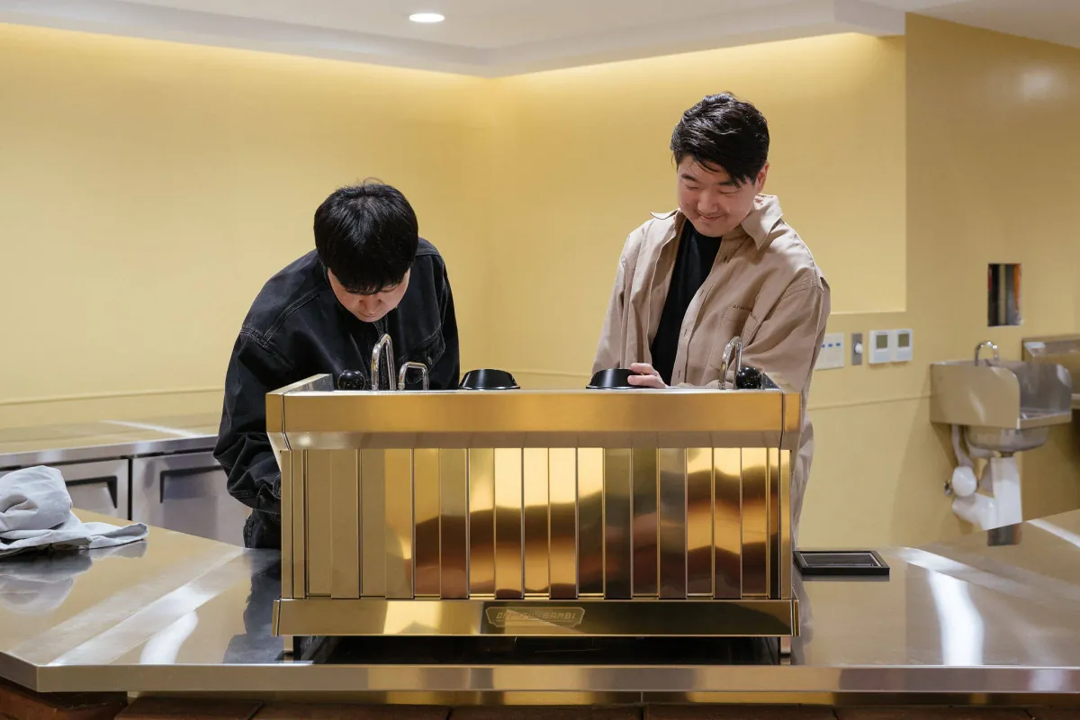 Two baristas behind the custom gold La Marzocco Strada AV at Kumquat DTLA