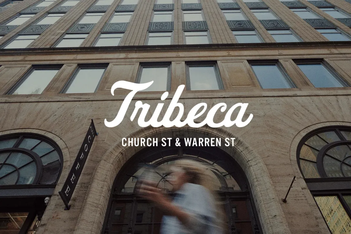 The stone arches and tall windows of the Tribeca building that houses Birch Coffee, with a black Birch Coffee flag over the entrance and the word Tribeca lettered across the photo