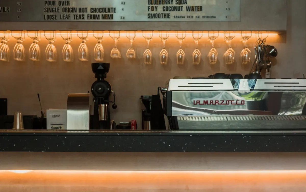 The bar at 640East in Wood Wharf, with a coffee grinder and espresso machine below a row of hanging glasses
