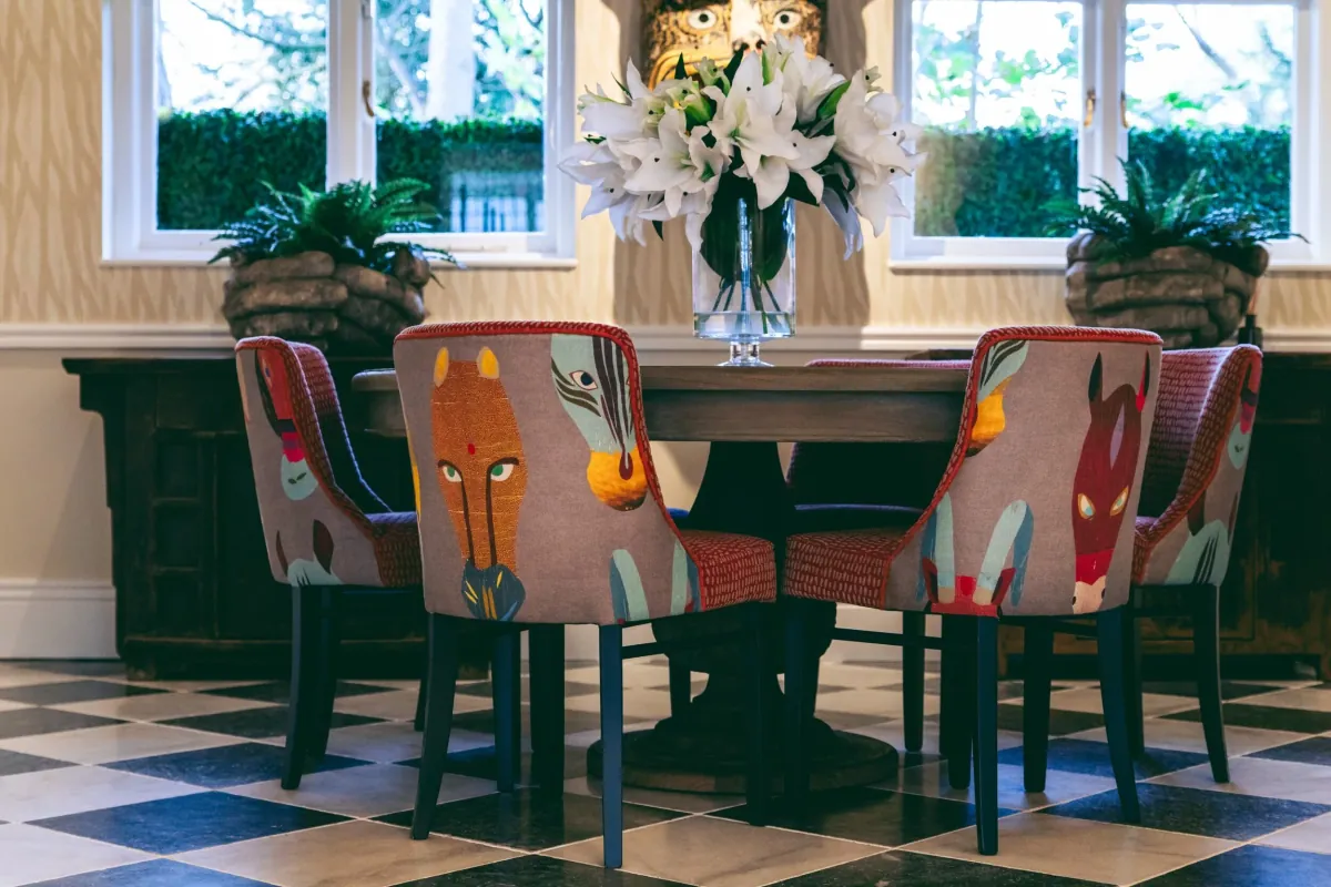 A round table with patterned armchairs, white lilies and a black-and-white chequered floor inside Bould Brothers in Cambridge