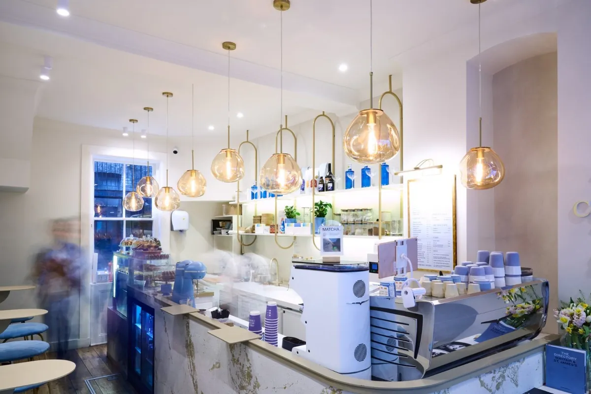 The marble counter, espresso machine and brass pendant lights inside Chill House in Mayfair