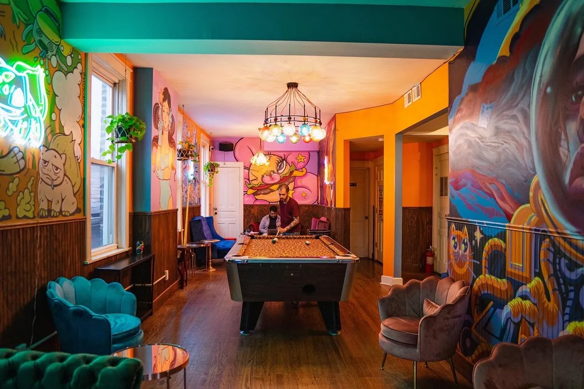 The upstairs room at Dark Matter's Star Lounge in Chicago, with a pool table, velvet shell chairs and murals on every wall