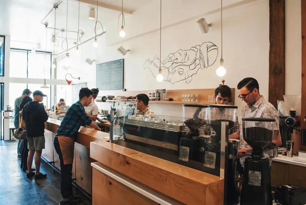 Baristas and customers at the long wooden espresso bar of the original Go Get Em Tiger in Larchmont Village