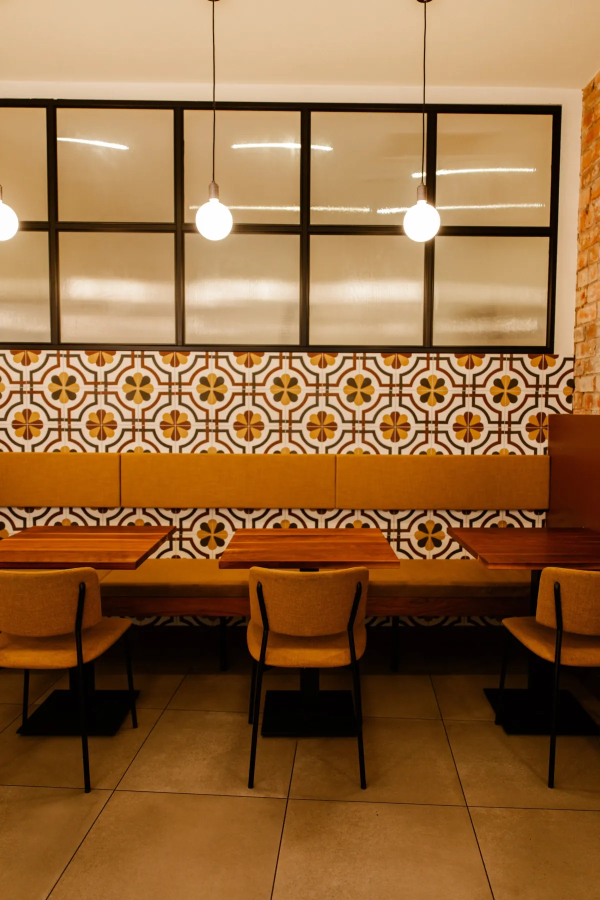 Orange booths and a patterned tile wall under black-framed windows inside Laynes in Leeds