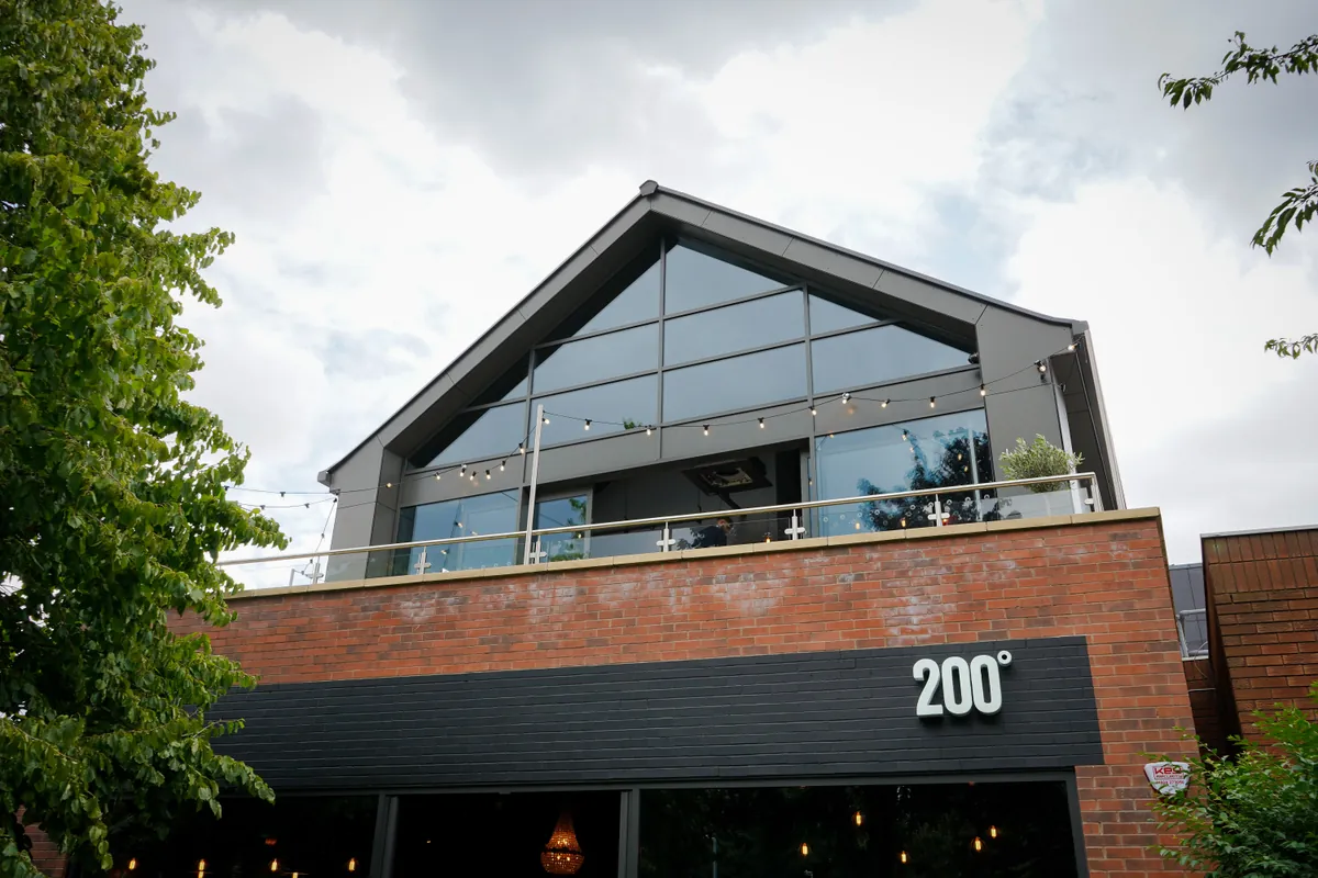 The 200 Degrees coffee shop in West Bridgford, a brick building with a glass-fronted rooftop terrace strung with lights