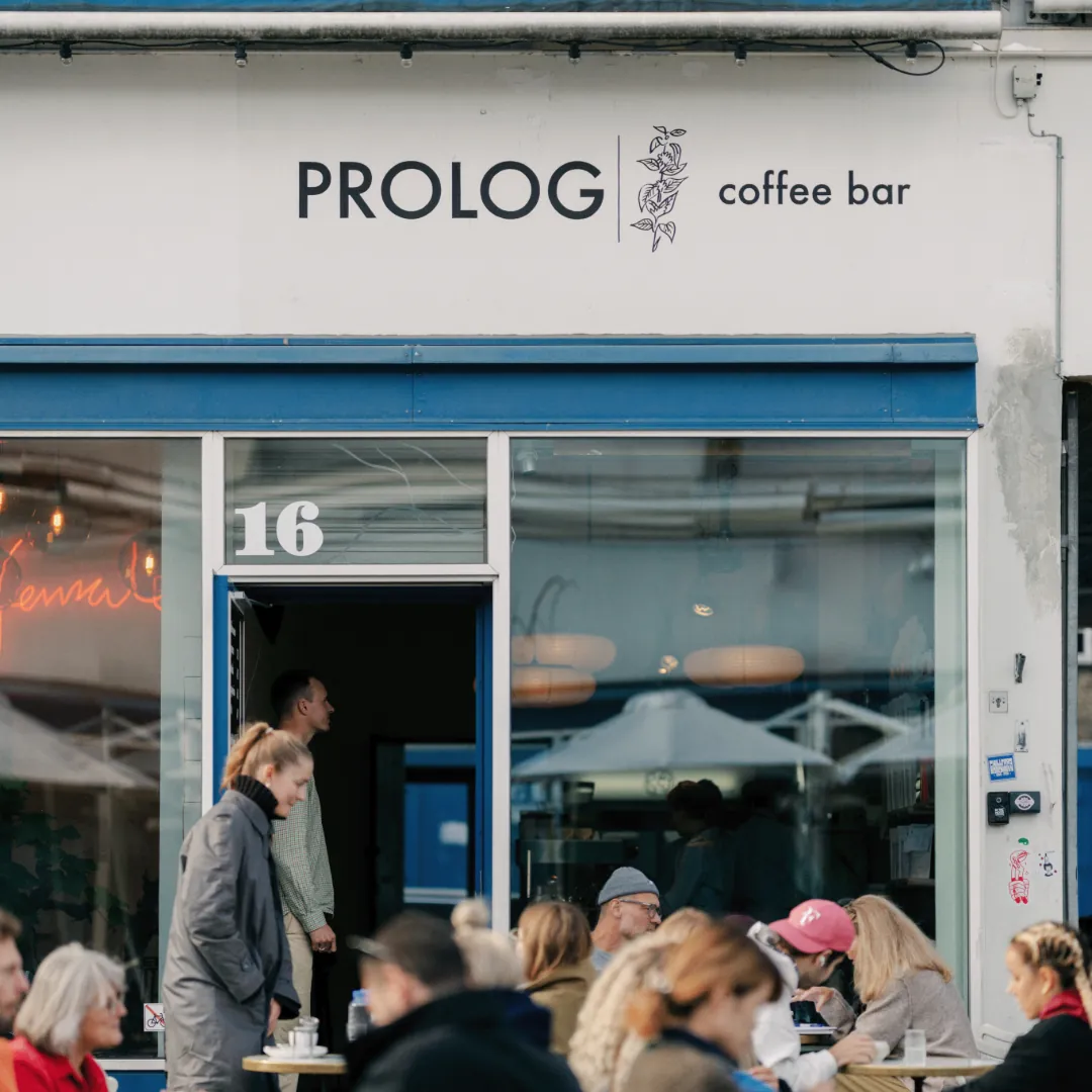 Guests outside the blue-framed front of the Prolog coffee bar in the Meatpacking District, under a white fascia reading Prolog coffee bar