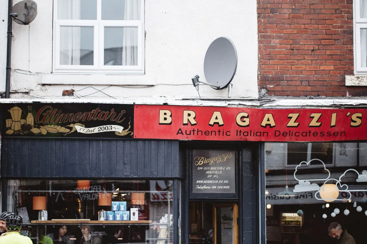 The shopfront of Bragazzi's on Abbeydale Road, with its red Authentic Italian Delicatessen sign and an Alimentari dal 2003 panel