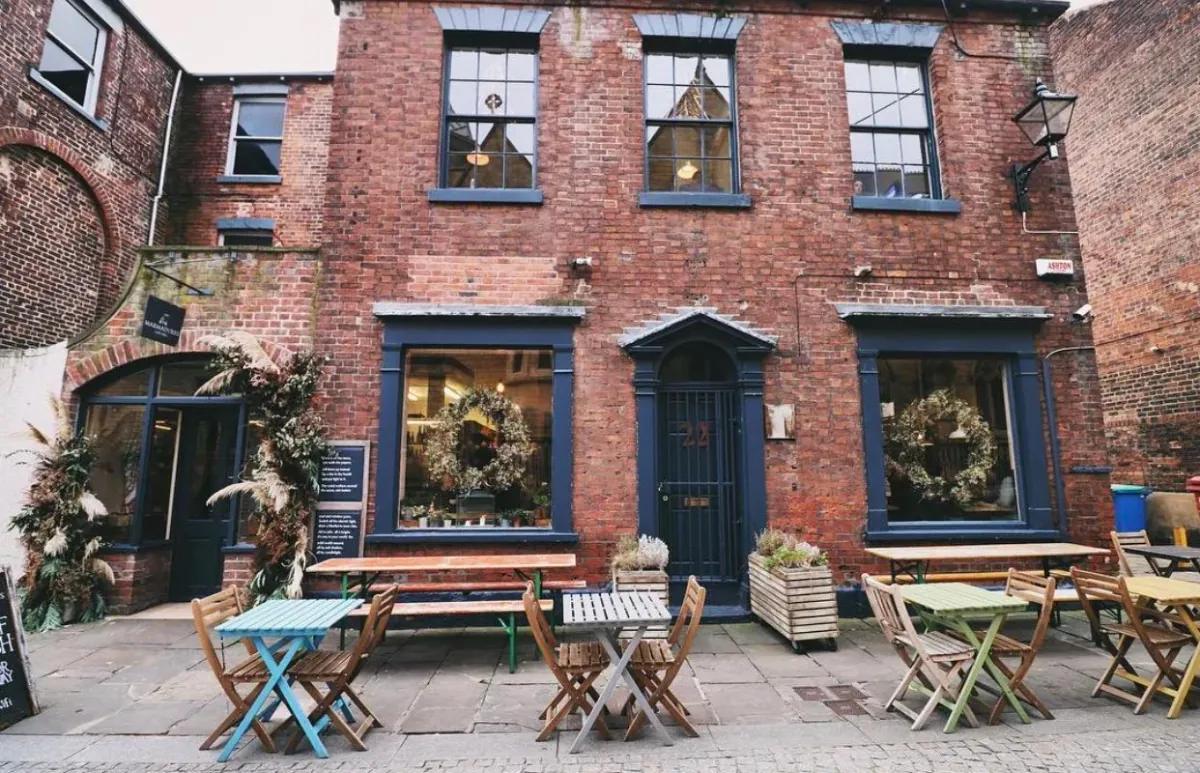 The red-brick townhouse of Marmadukes on Norfolk Row, with wreaths in the windows and pastel tables and chairs on the cobbles outside