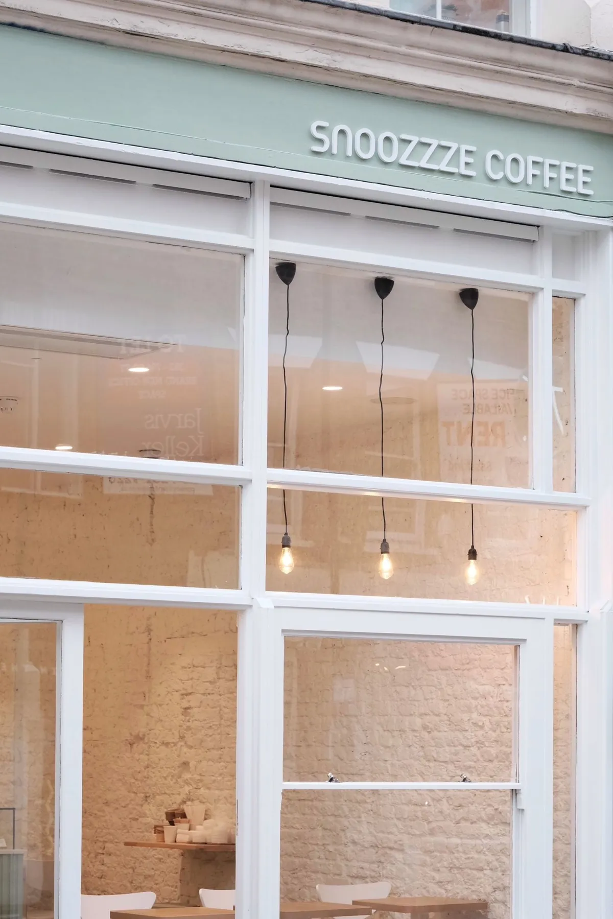 The pale green shopfront of Snoozzze Coffee, with its name above tall white-framed windows