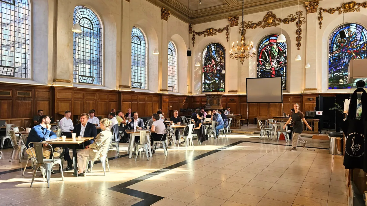 Café tables across the floor of St Nicholas Cole Abbey, under tall arched windows and stained glass