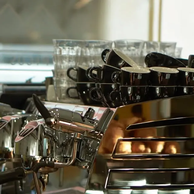 Stacks of black cups and glasses on top of the chrome espresso machine at Los Picos Café in Russafa