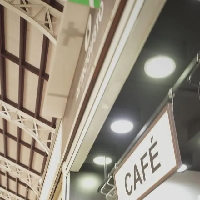 A hanging Café sign beside the Retrogusto Coffeemates counter, under the iron roof trusses of Valencia's Mercado Central