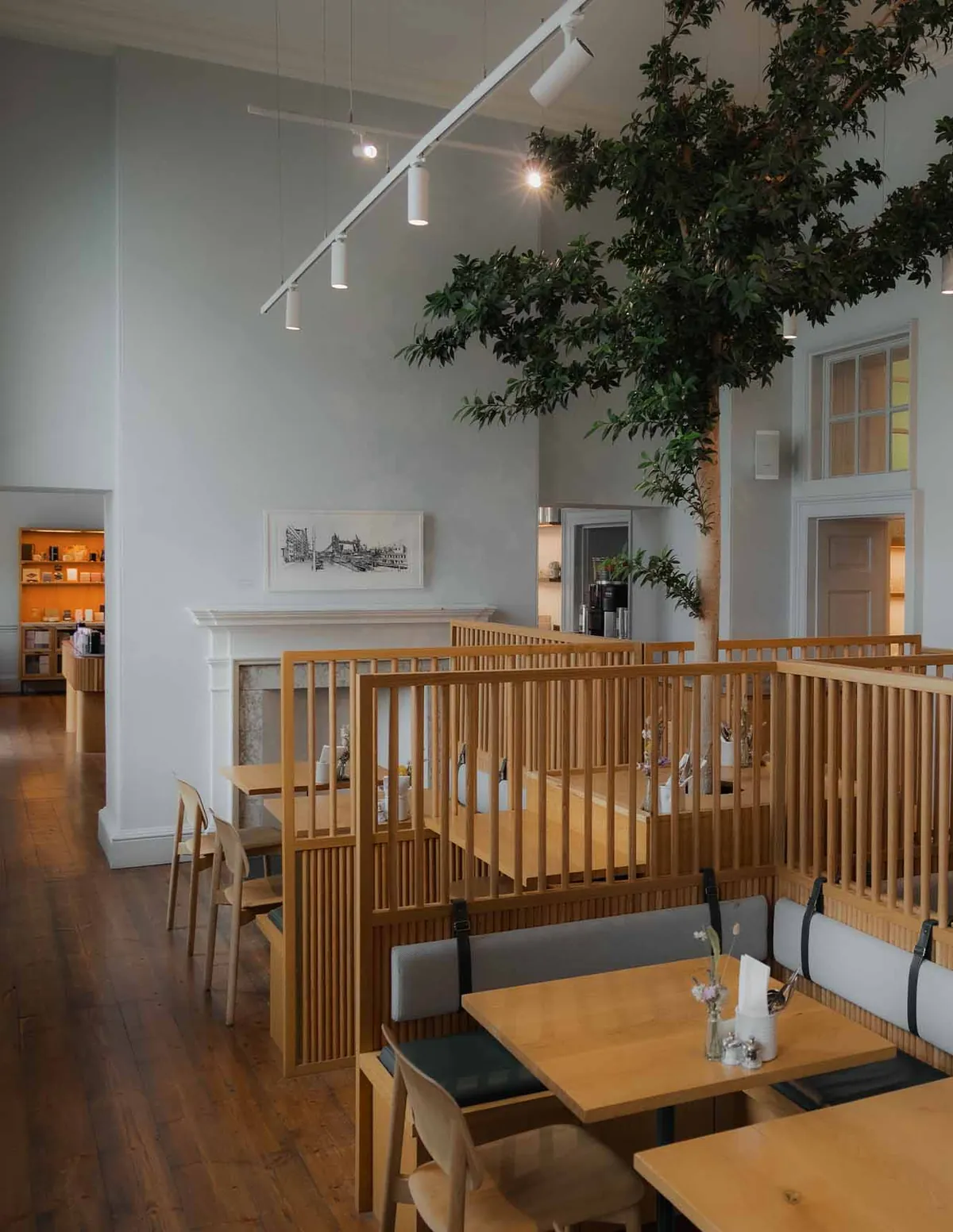 Timber booths beneath a living tree in the high-ceilinged room at WatchHouse Somerset House