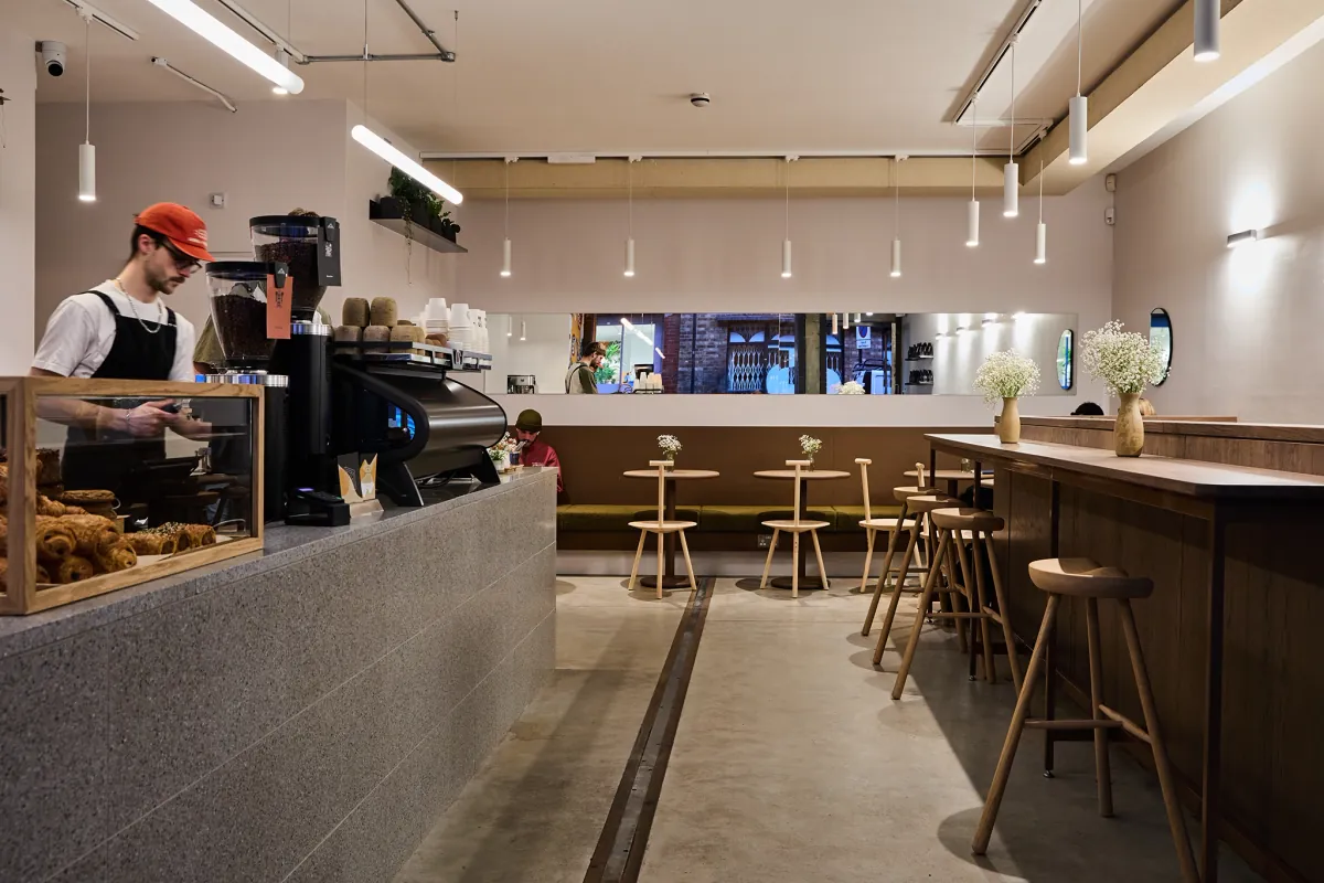 The Origin Coffee flagship in Shoreditch, with a terrazzo counter, pastries under glass and stools along a wooden bar