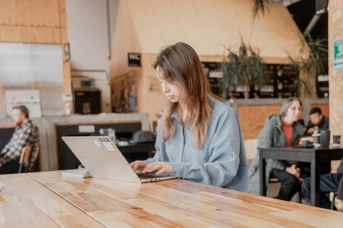 A customer working on a laptop at the long timber table inside 92 Degrees in the Baltic Triangle