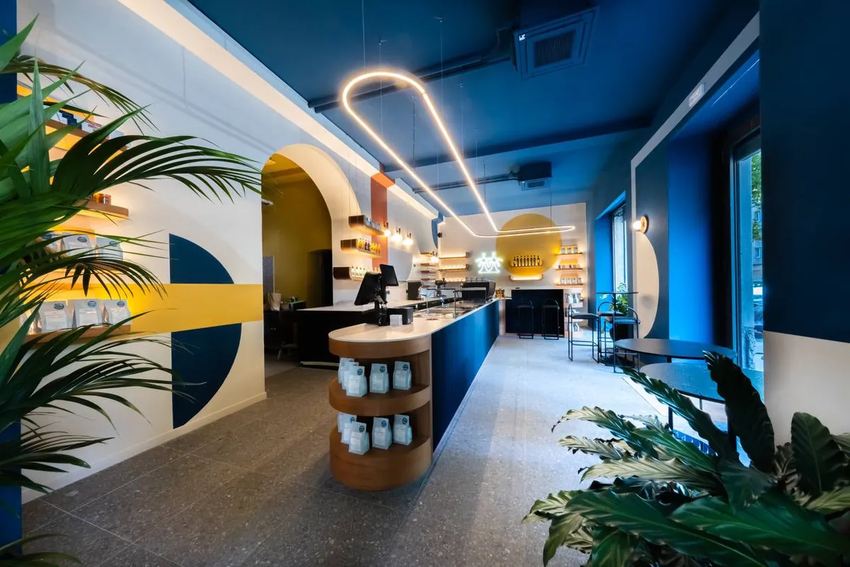 The Cafezal Coffee Hub, with blue and ivory walls, a curved neon light and a central bar