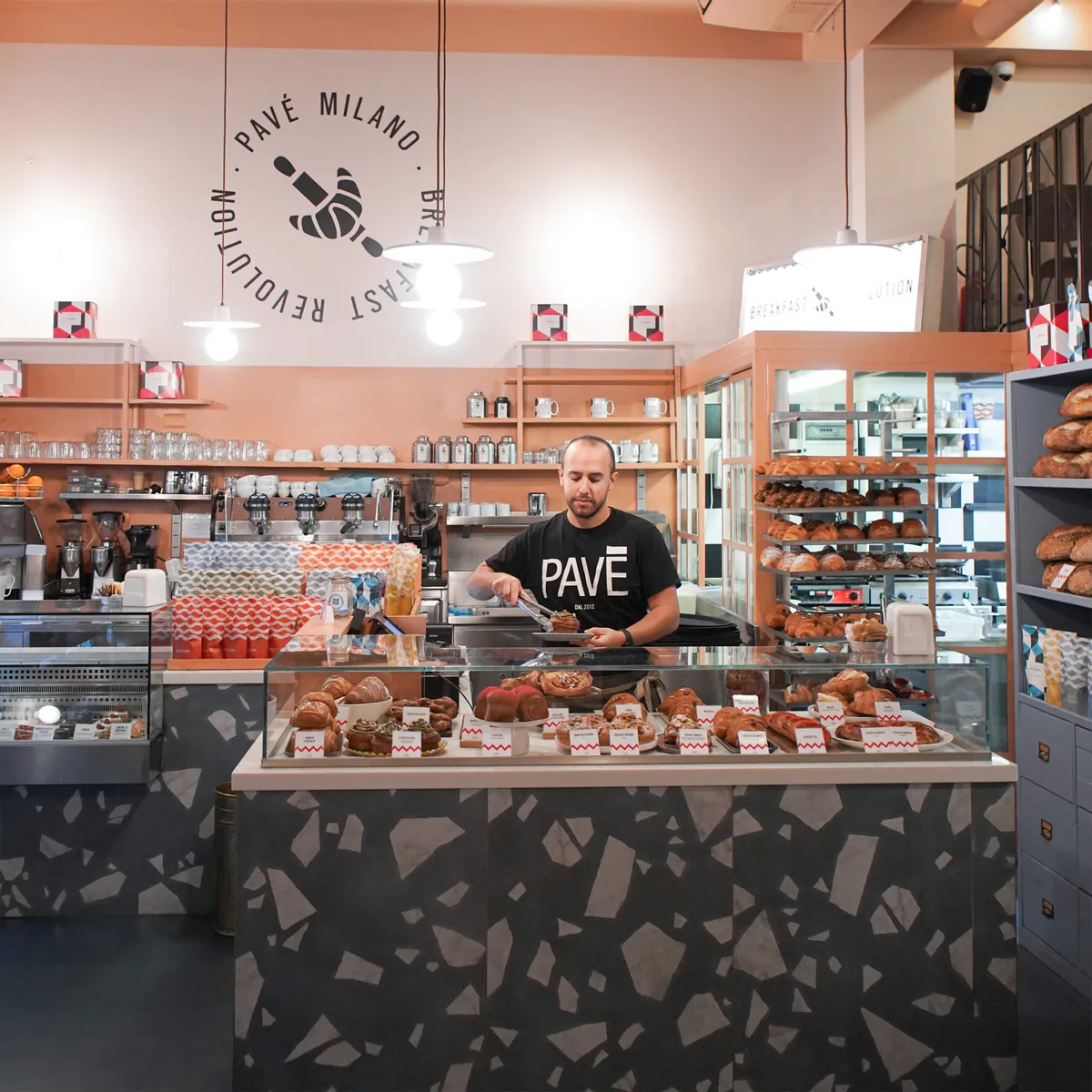 The counter at Pavé’s Porta Venezia shop, with pastries on display and the words breakfast revolution on the wall