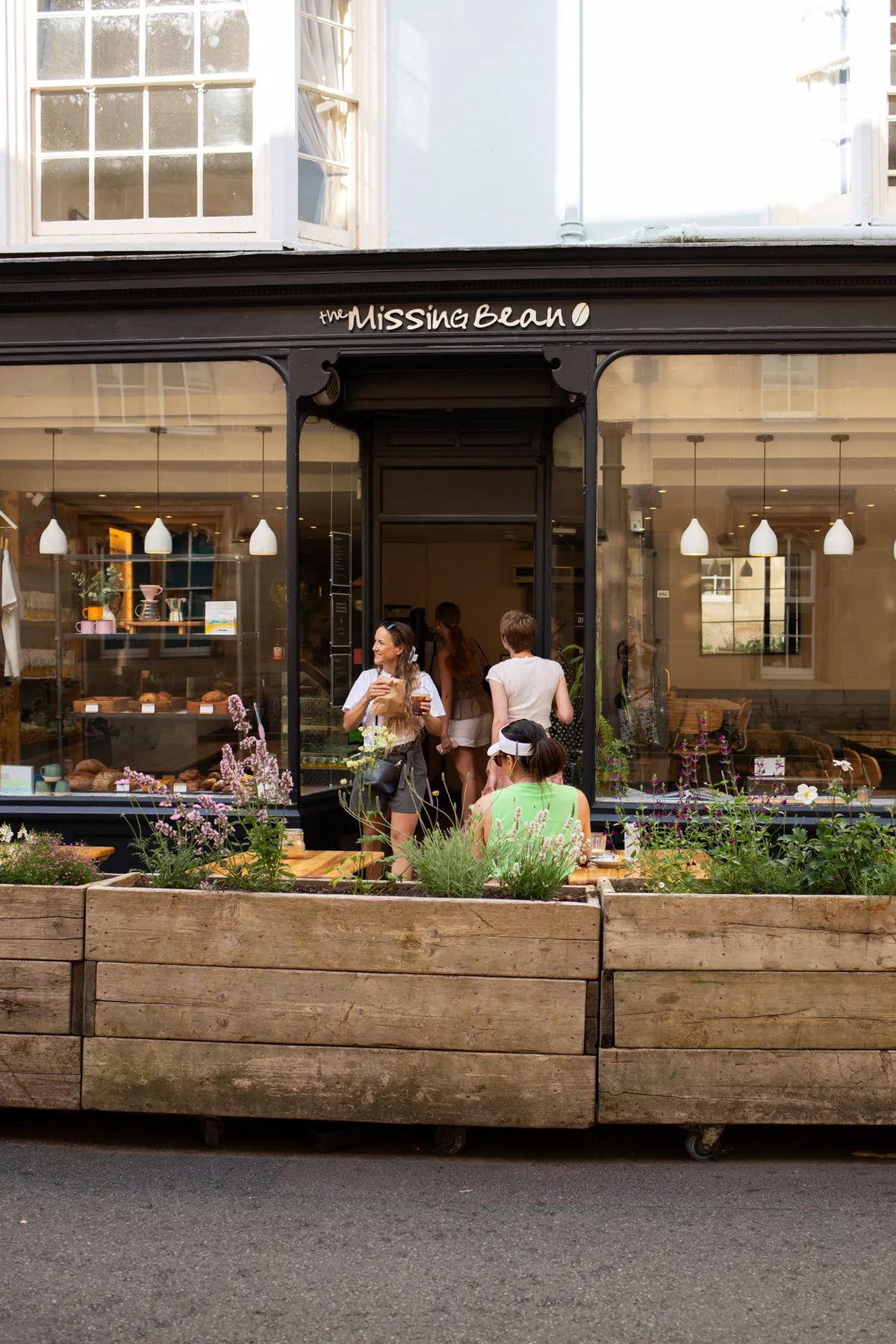The dark shopfront of Missing Bean’s original café in central Oxford, with wooden planters of lavender and customers at the window counter
