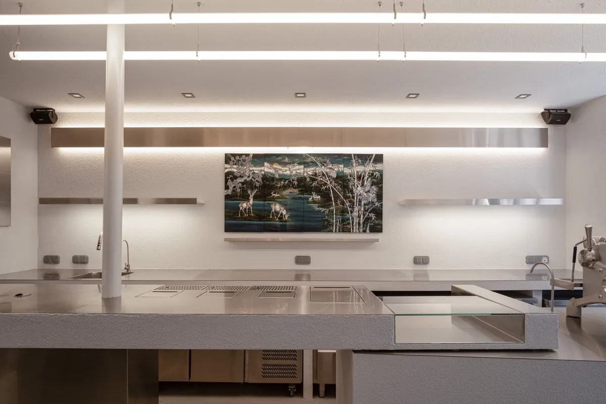 The brushed-steel counter and white plaster walls of Tiba, with a landscape artwork on the back wall
