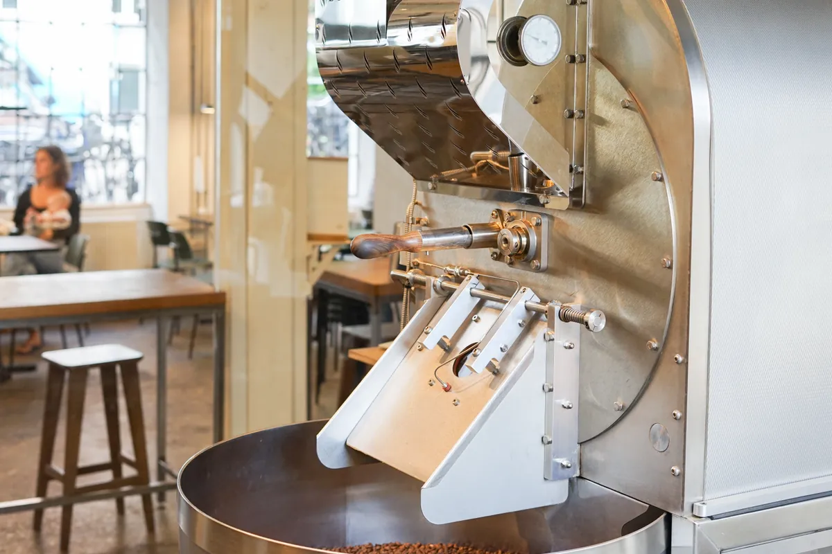The roaster beside the seating in Coffee Collective's Frederiksberg café, with its cooling tray in the foreground