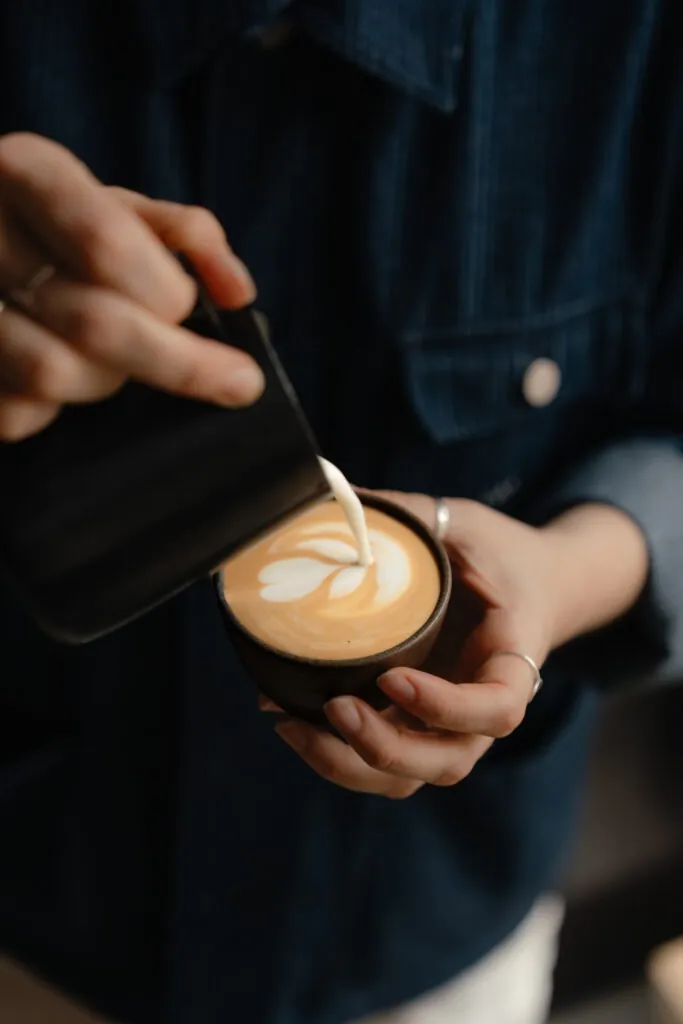 A barista pouring latte art into a cup at the DAK Showroom