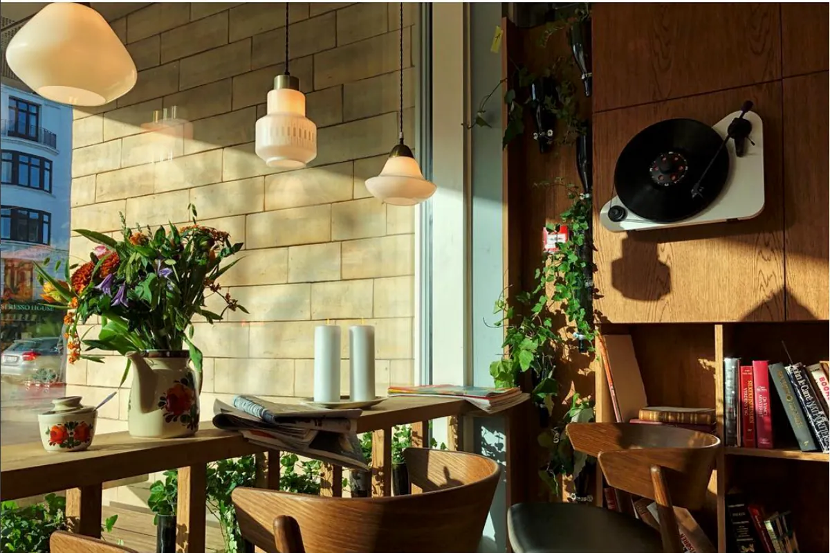 A Riccos bar with wooden tables, a window counter with flowers and a record player on the shelves