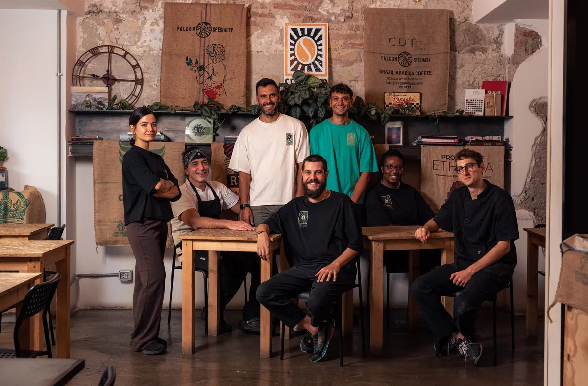 The Sensorio team at the café’s wooden tables, with coffee sacks and a clock on the brick wall behind them