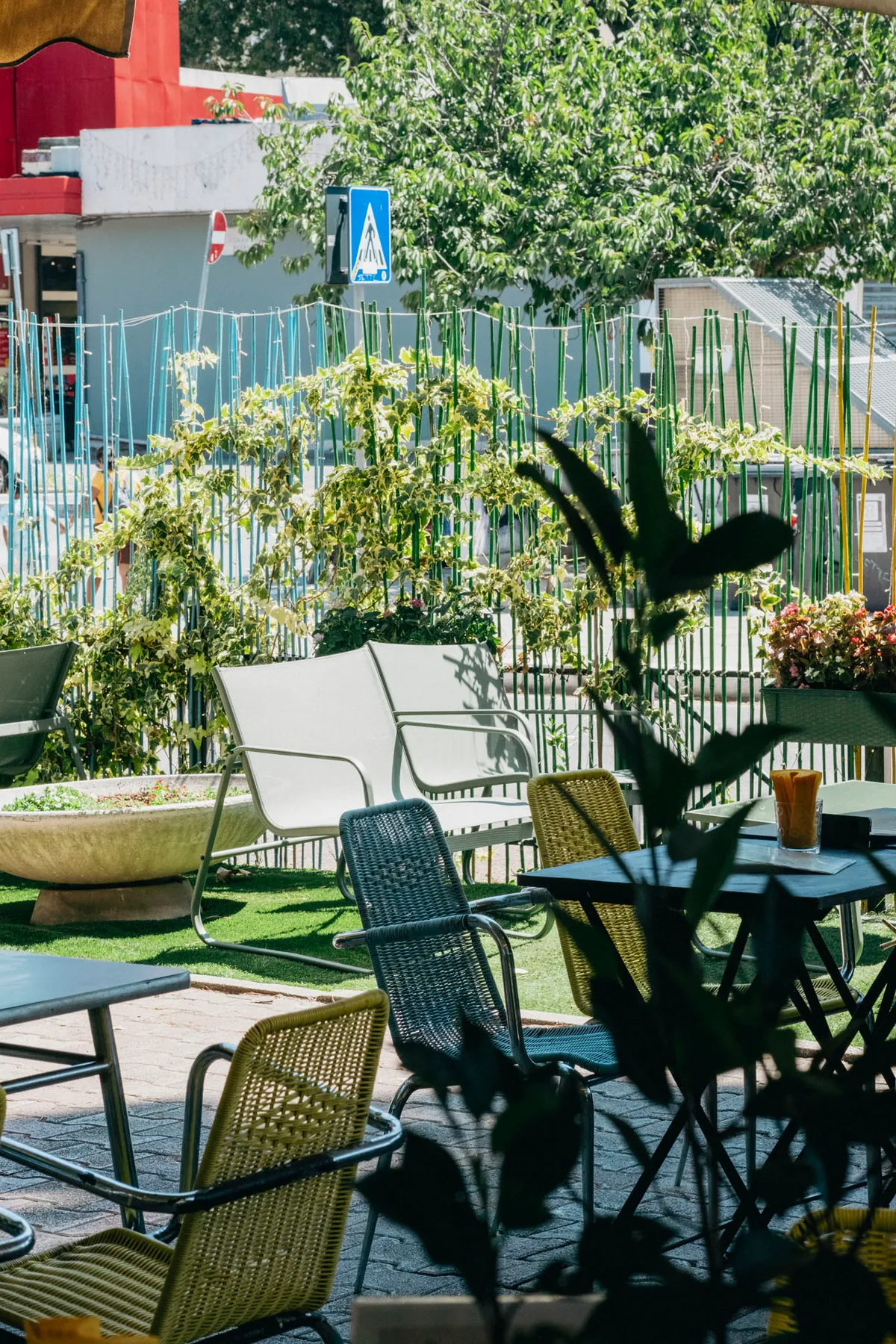 Outdoor seating at Tram Depot under the trees, with green garden chairs and planters around a tiled terrace