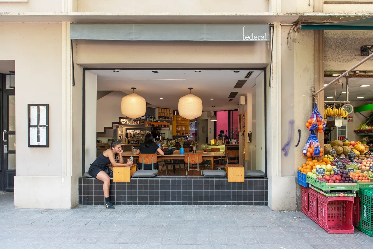 The open shopfront of Federal in Sant Antoni, with people at the window bench and a fruit stall next door