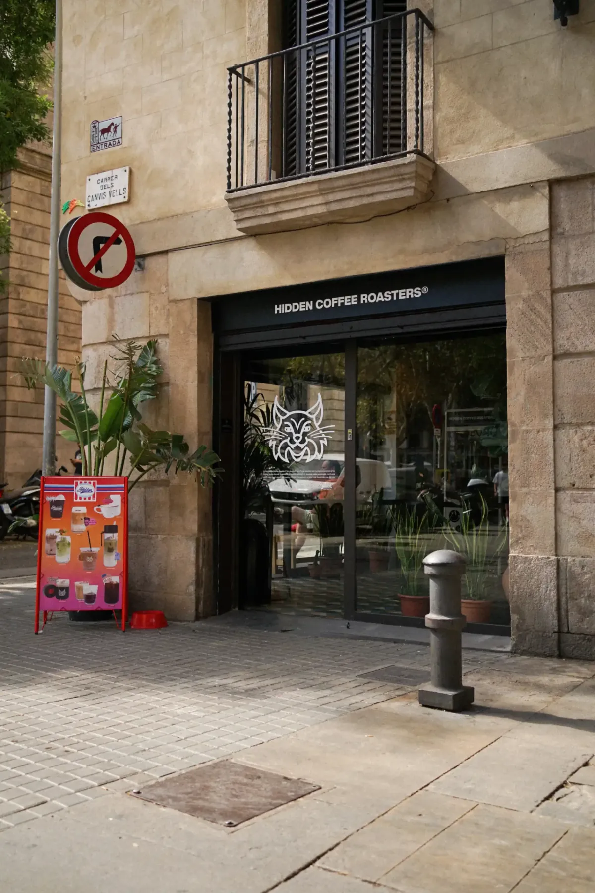 The El Born shopfront of Hidden Coffee Roasters, a glass door under a black sign in an old stone building