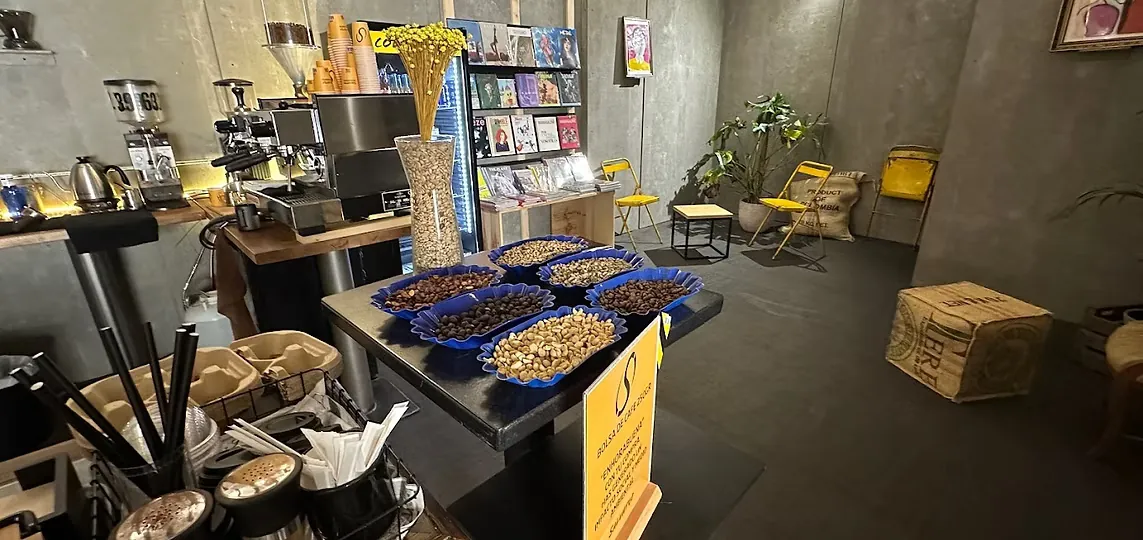 Inside Salvatge Coffee in Gràcia, with trays of coffee beans on a table, grinders on the bar and yellow chairs at the back