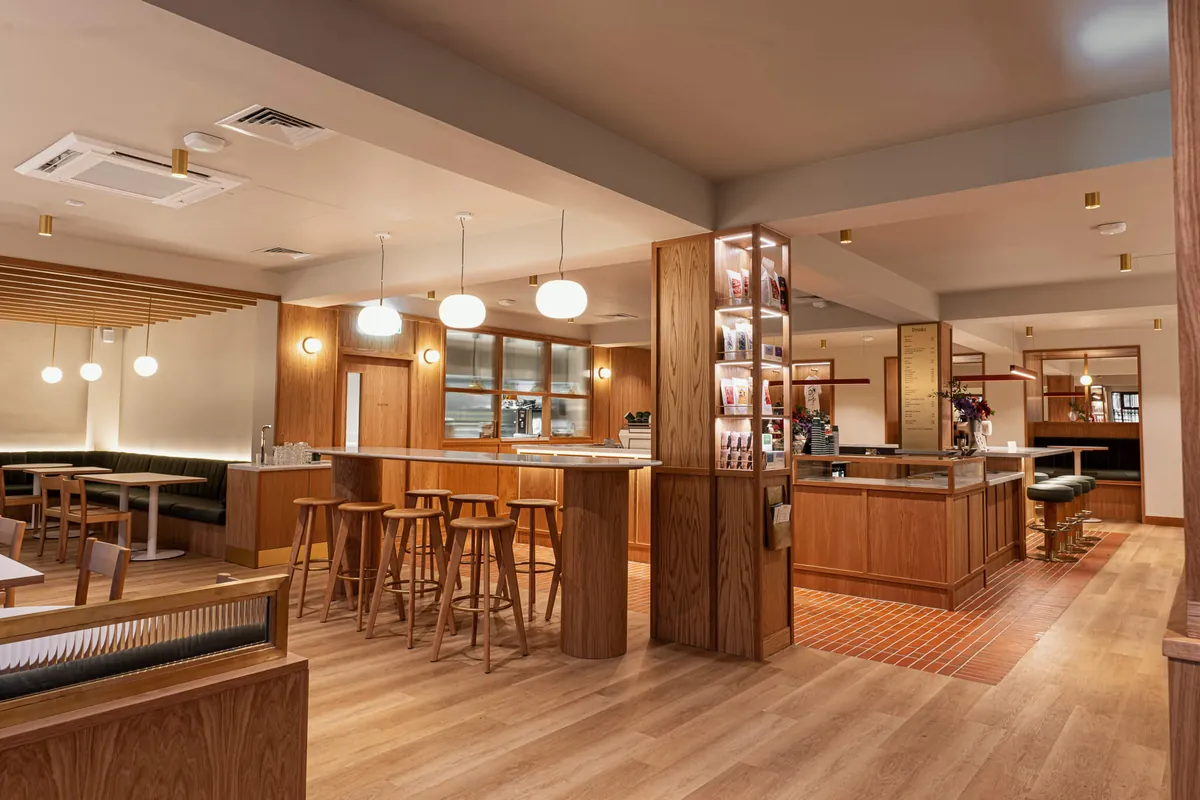 The dining room at Neighbourhood in Belfast, with wooden bar stools, green banquettes and globe pendant lights