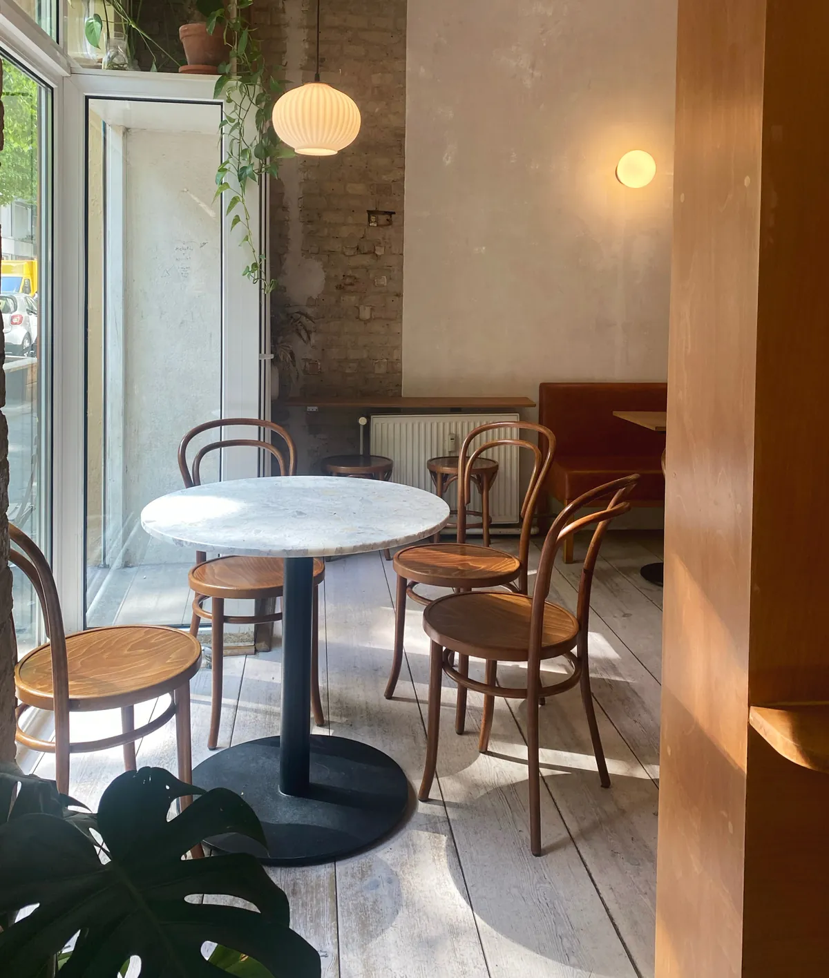 A marble bistro table and bentwood chairs by the window inside the Companion Tea & Coffee café