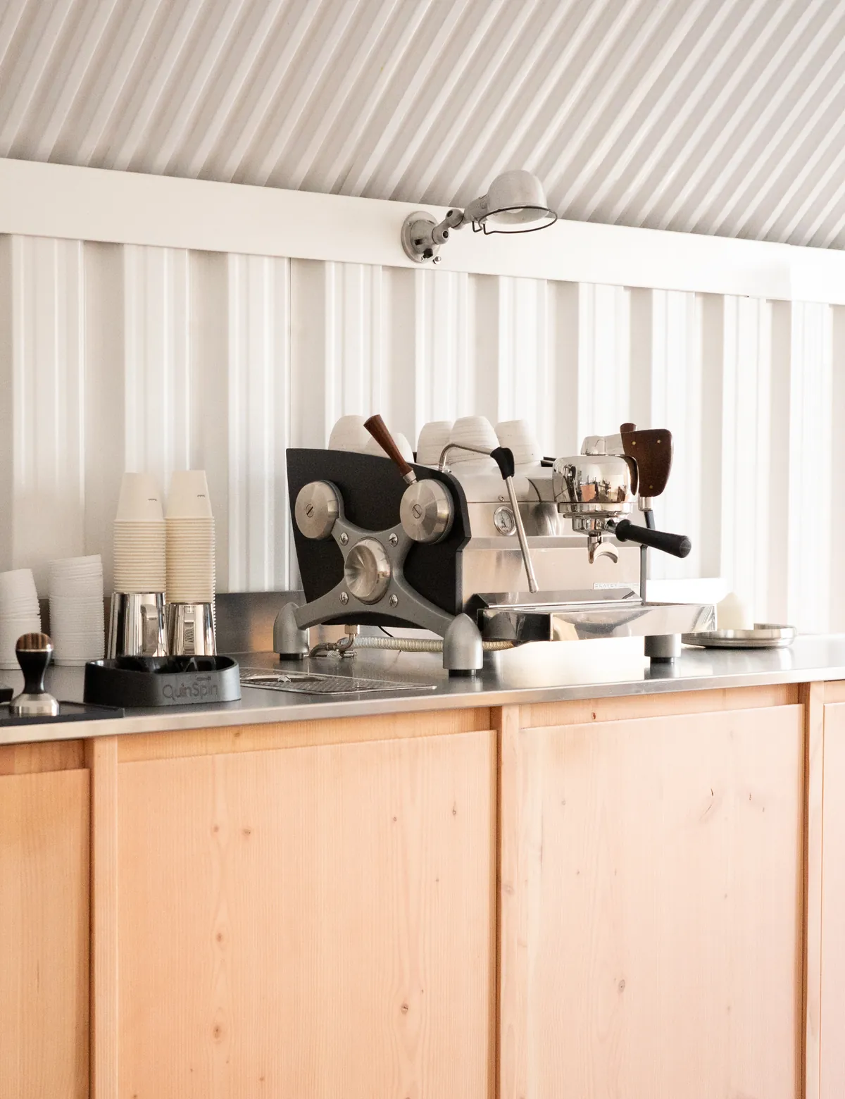 The tasting-room counter at the Obadiah roastery, with an espresso machine and stacked cups against a white corrugated wall