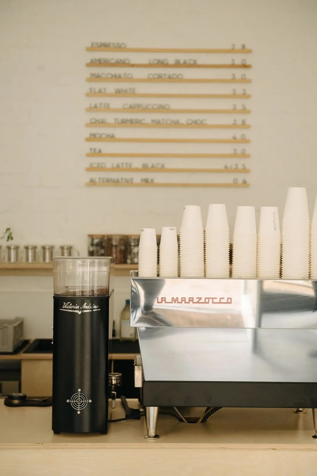 The espresso bar at Compane, with a La Marzocco machine, stacked cups and a letter-board menu on the wall