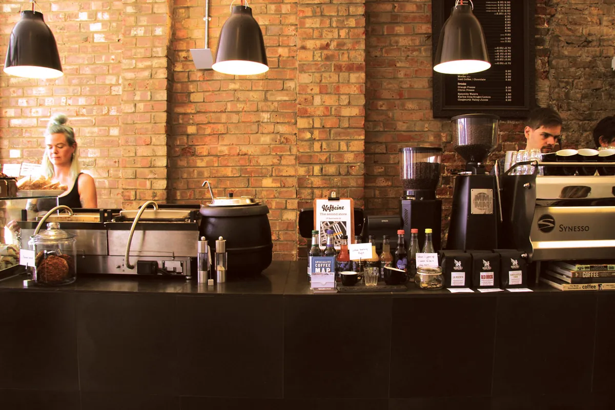 The counter at Kaffeine in Fitzrovia, with a Synesso espresso machine against a bare brick wall