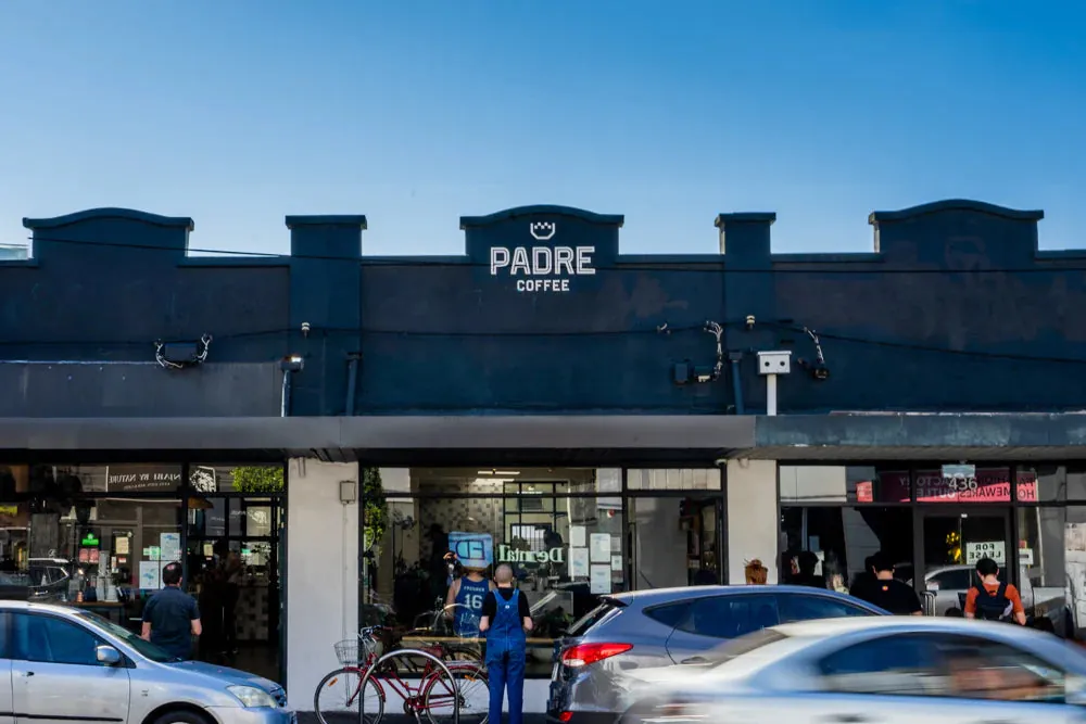 The dark blue shopfront of Padre Coffee in Brunswick East, with the Padre Coffee sign on the parapet