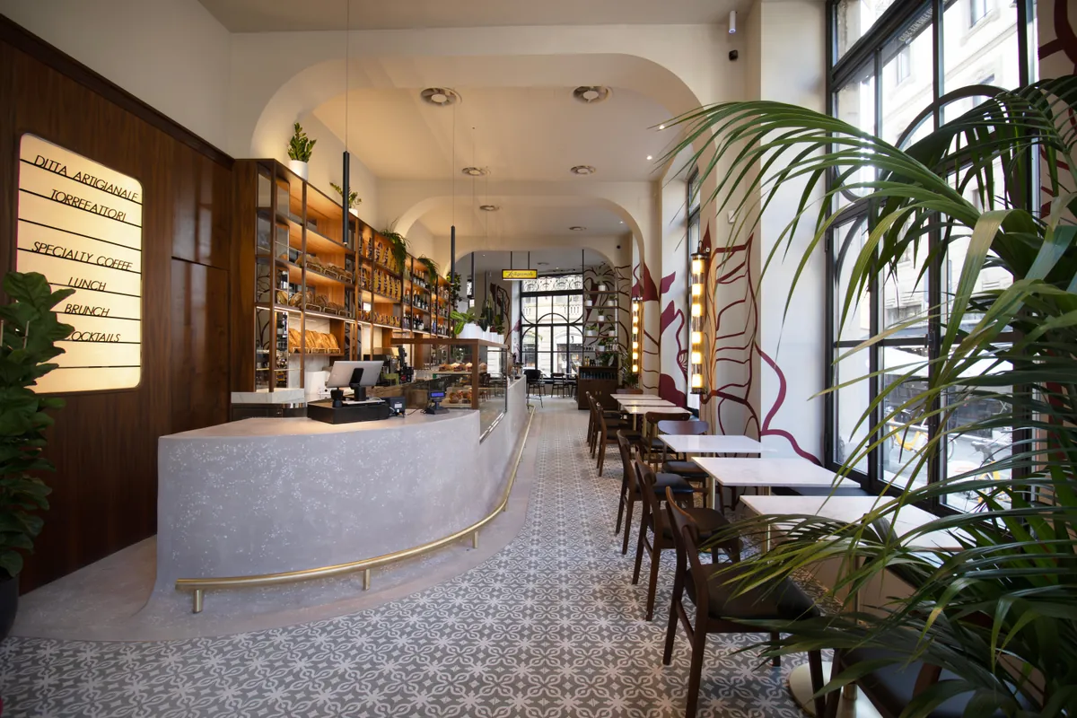 The long curved marble counter at Ditta Artigianale in the Magenta district, with patterned floor tiles, café tables and tall windows