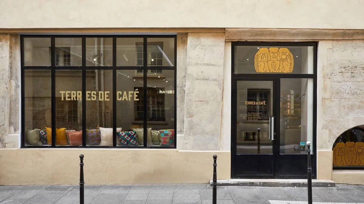 The stone frontage of Terres de Café in the Marais, with the name across the window and cushions along the window seat