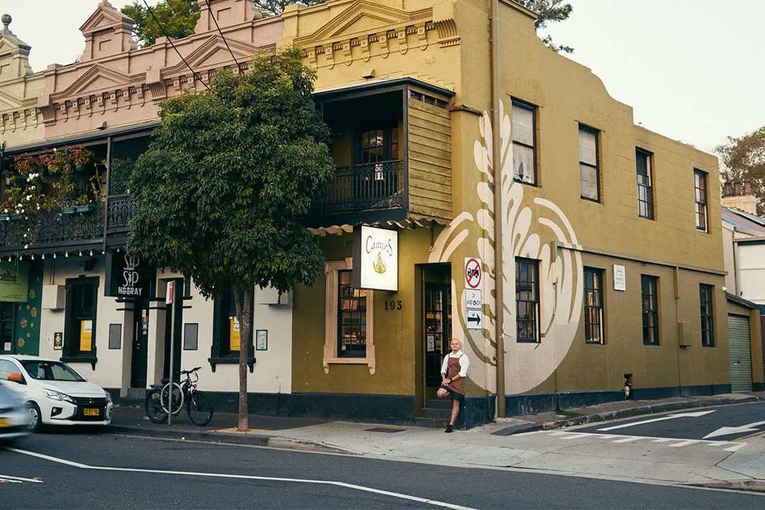 The mustard-yellow corner terrace of Campos Coffee in Newtown, with a barista in the doorway