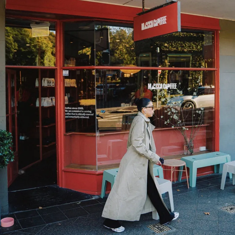 The red shopfront of Mecca Coffee in Paddington, with a person walking past